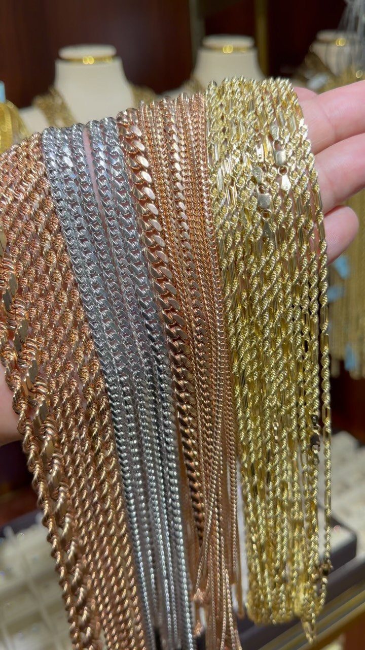 Various gold and silver chains held in a hand, showing different link styles.