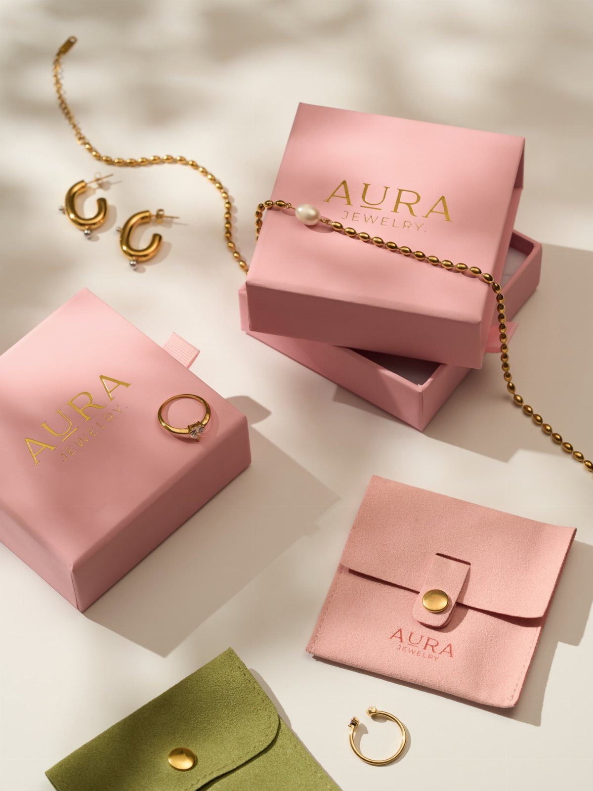 19 Jewelry Posting Ideas for Instagram That Build Sales 8 Gold ring, earrings, and pearl necklace displayed with pink Aura Jewelry boxes.
