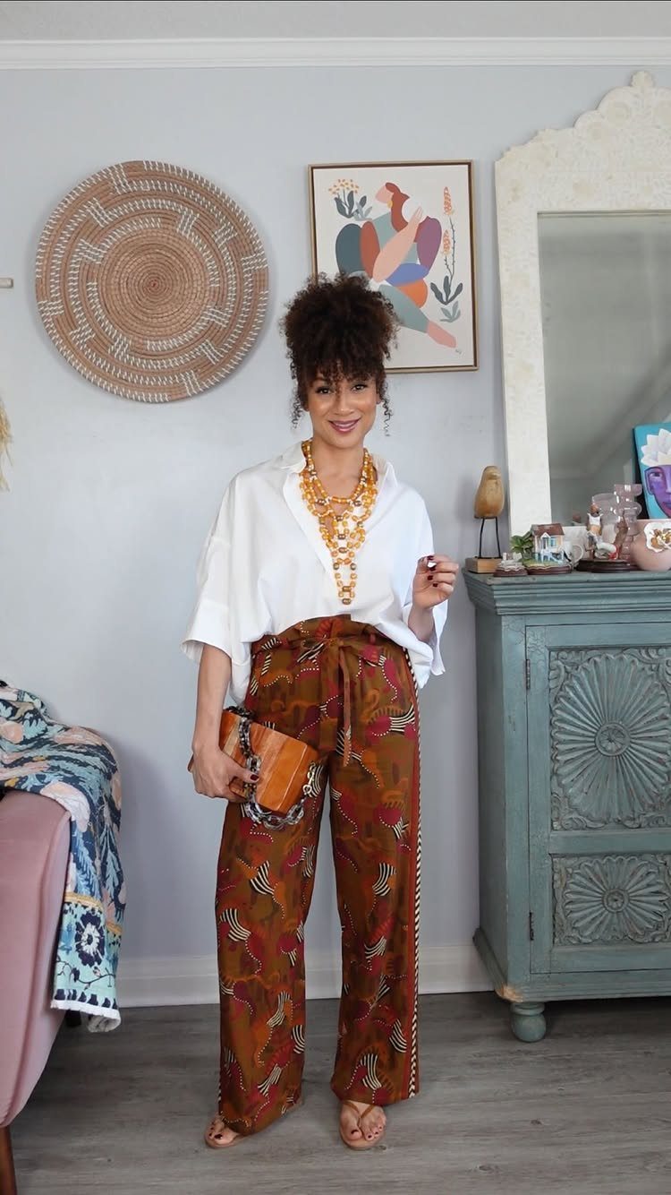 19 Jewelry Posting Ideas for Instagram That Build Sales 4 Woman wearing a chunky gold statement necklace with a white blouse and patterned trousers.