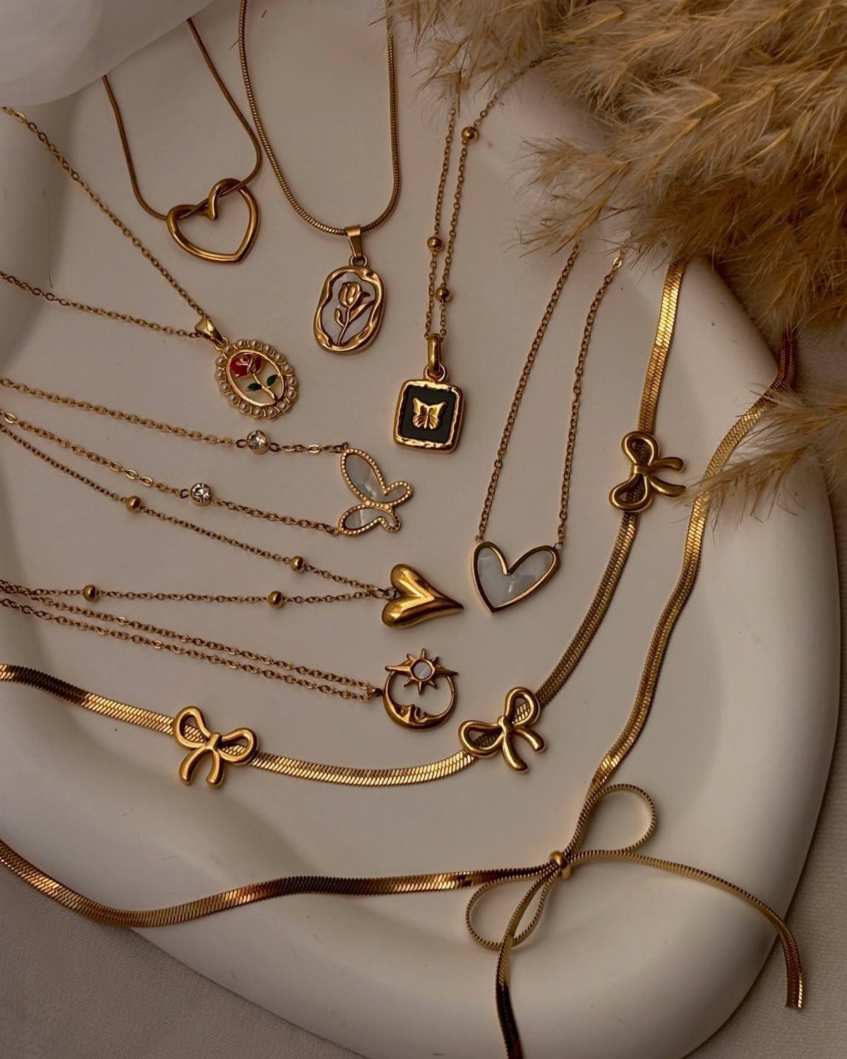 19 Jewelry Posting Ideas for Instagram That Build Sales 9 Gold necklaces with heart and bow pendants arranged on a white ceramic tray.