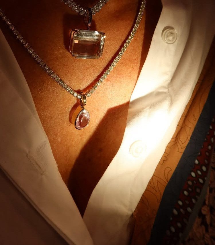 19 Jewelry Posting Ideas for Instagram That Build Sales 12 Two layered necklaces with clear and pink gemstone pendants worn with white shirt.
