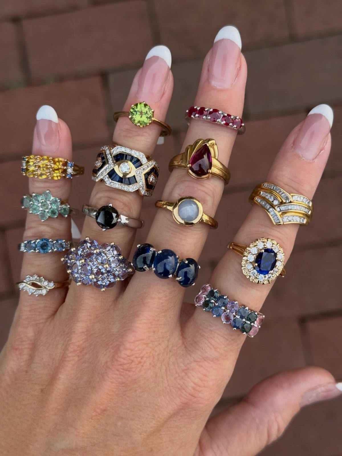 19 Jewelry Posting Ideas for Instagram That Build Sales 2 Hand wearing multiple colorful gemstone rings on every finger against a brick background