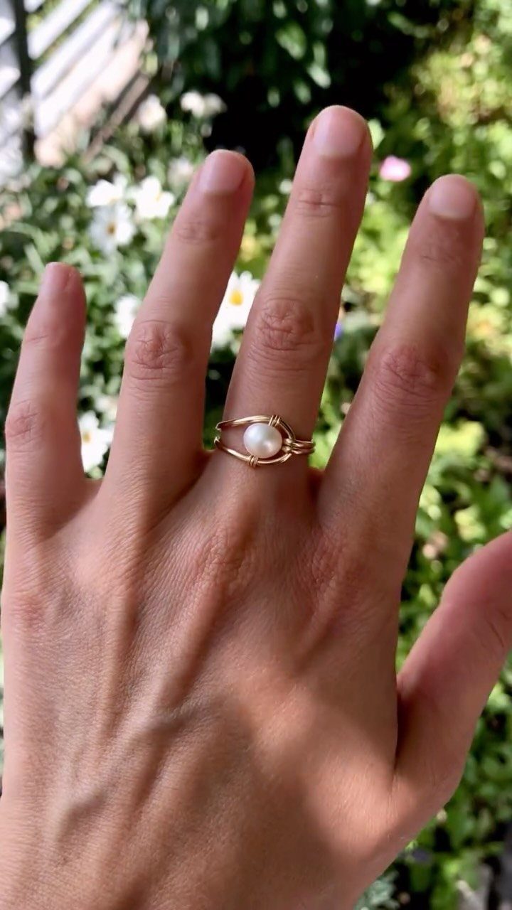 19 Jewelry Posting Ideas for Instagram That Build Sales 16 Gold pearl ring on a hand with a blurred garden background