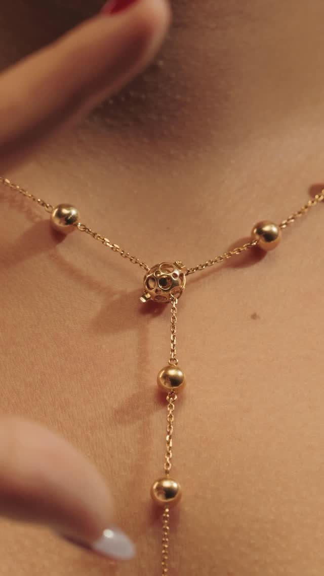 19 Jewelry Posting Ideas for Instagram That Build Sales 7 Gold bead necklace with a central ornament worn on a person's neck.