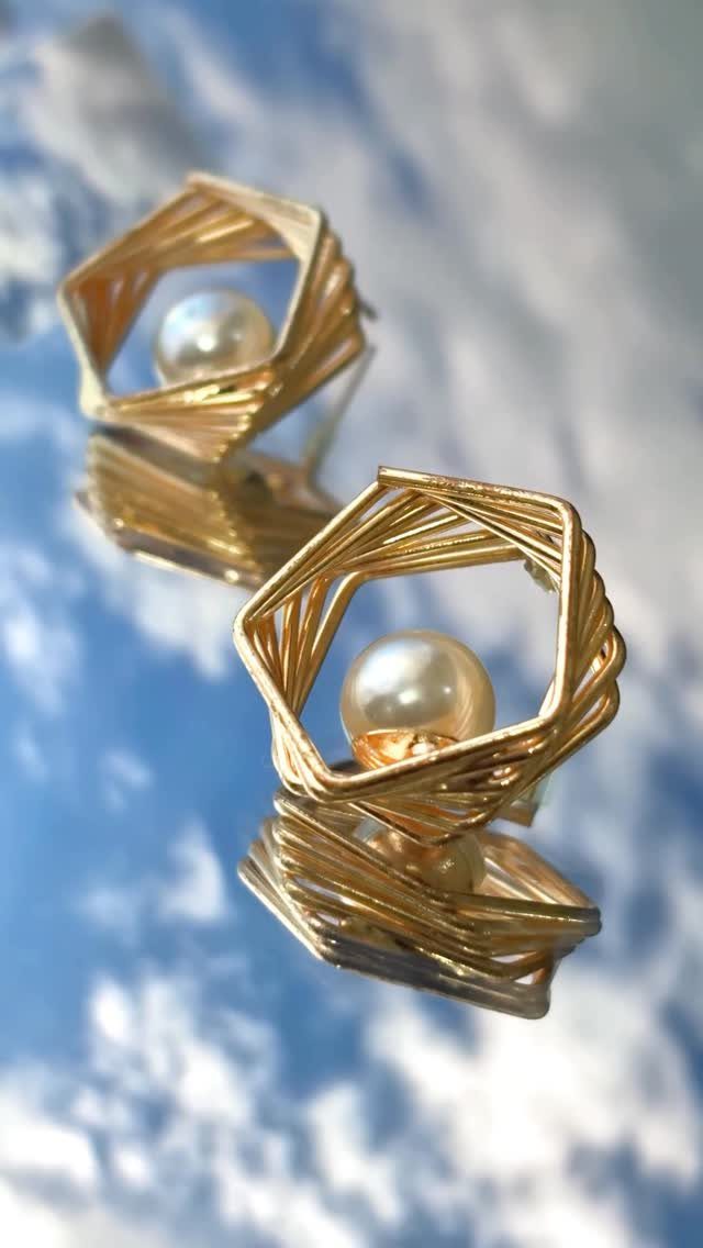 19 Jewelry Posting Ideas for Instagram That Build Sales 11 Gold geometric earrings with white pearls reflecting on a blue sky surface.