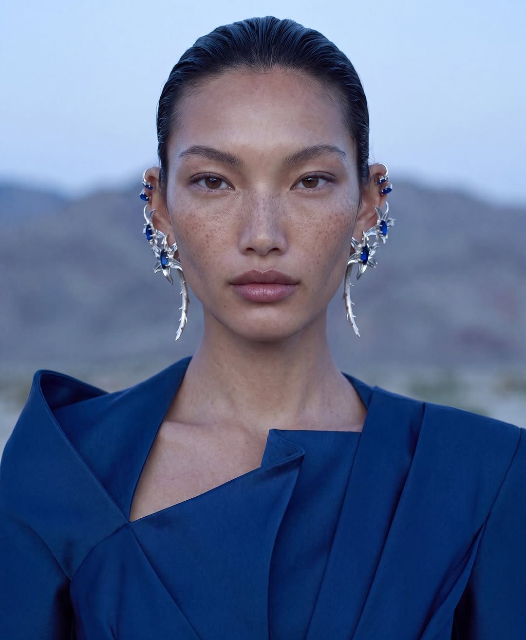 12 Jewelry Stack Inspo Earrings Ideas 12 Woman wearing elaborate silver and blue gemstone earring stacks in both ears.