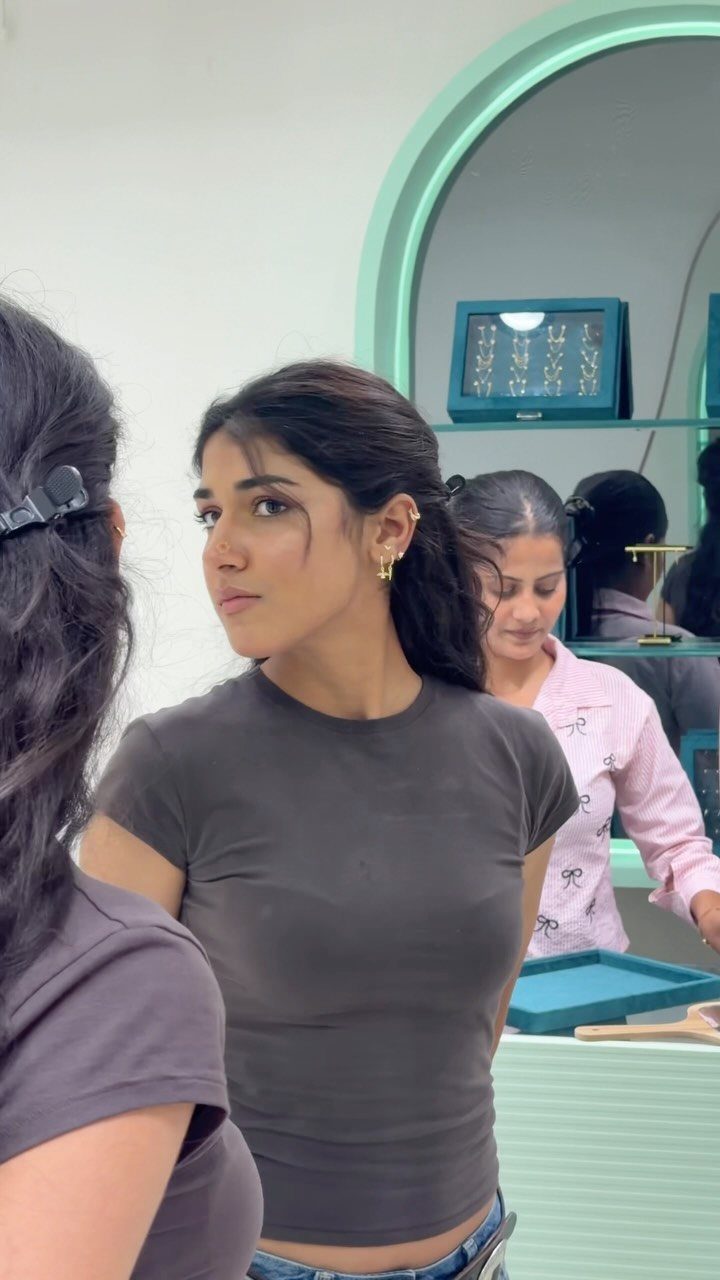 12 Jewelry Stack Inspo Earrings Ideas 2 Woman wearing a gold ear cuff and hoop earrings in a jewelry store
