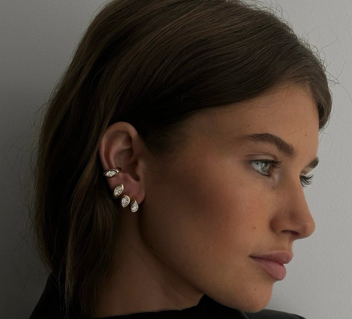12 Jewelry Stack Inspo Earrings Ideas 10 Woman's ear with a stack of three gold teardrop gemstone stud earrings.