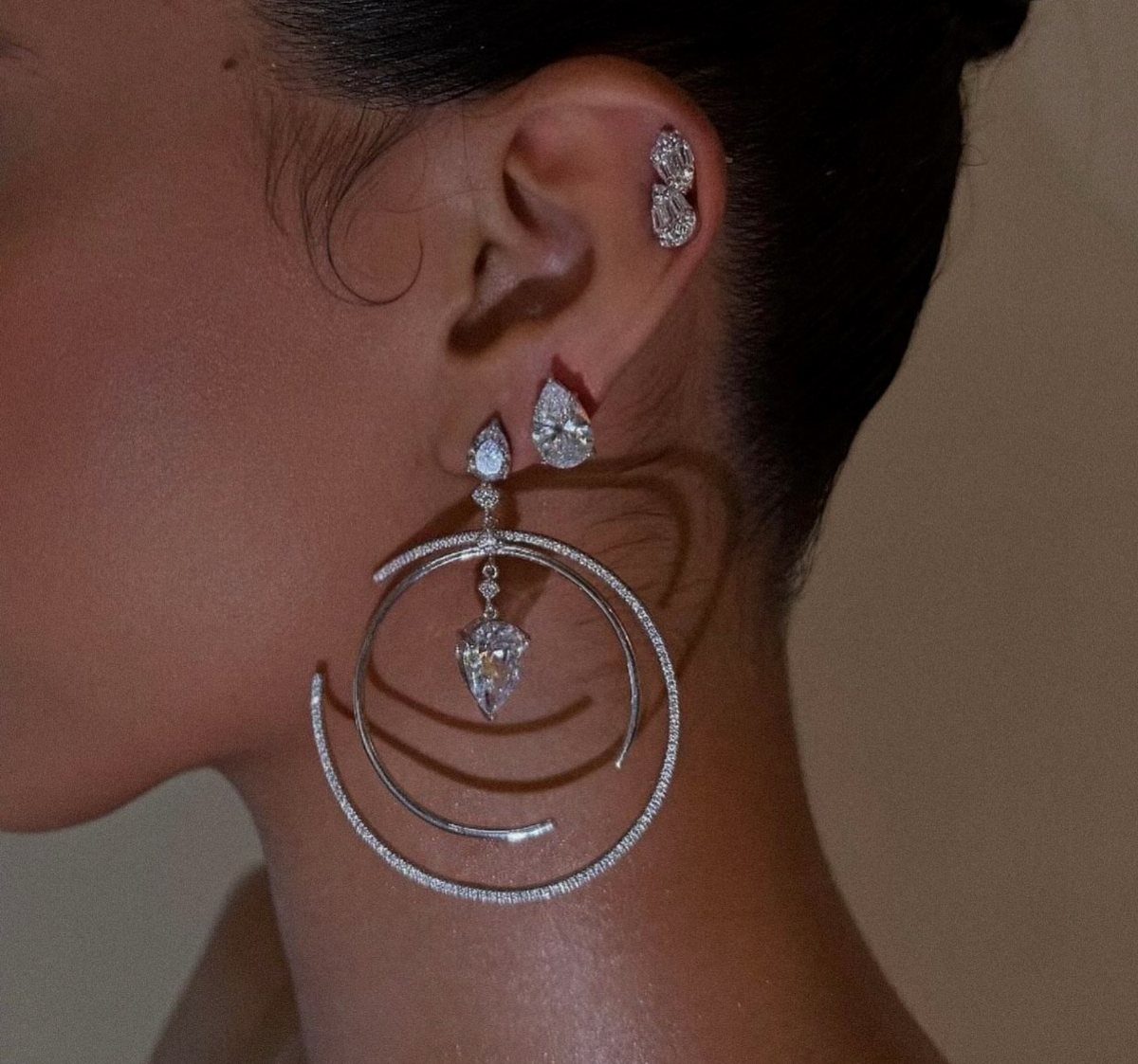 12 Jewelry Stack Inspo Earrings Ideas 11 Silver diamond earrings including a large spiral drop and cartilage studs on an ear.