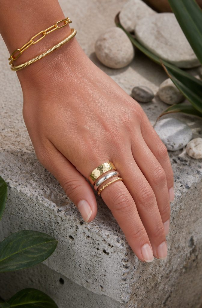 Maximalist Jewelry Gold: Oversized Earrings, Chunky Necklaces and the Full Trend 3 A model's hand adorned with a variety of stacked rings in different styles.