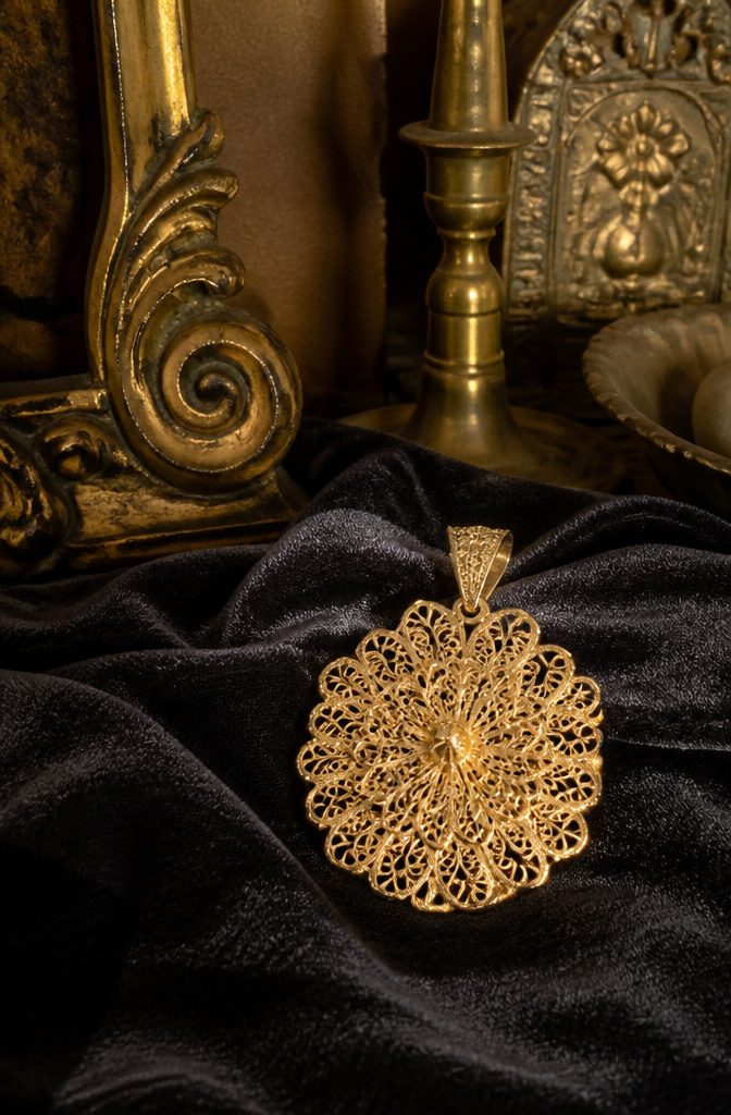 A gold filigree pendant showcasing detailed lace-like patterns.