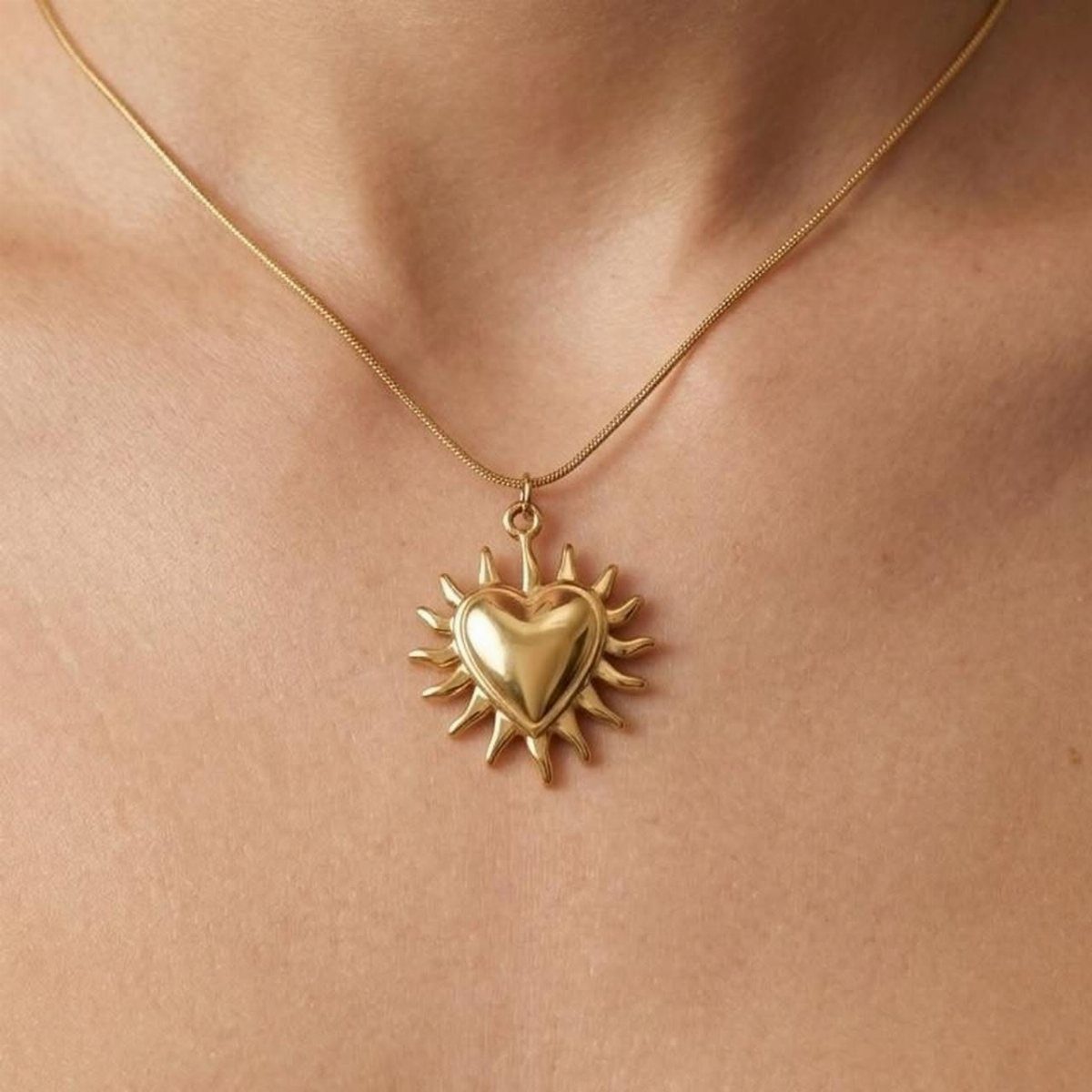 Gold chain necklace with a heart pendant surrounded by sun rays on skin