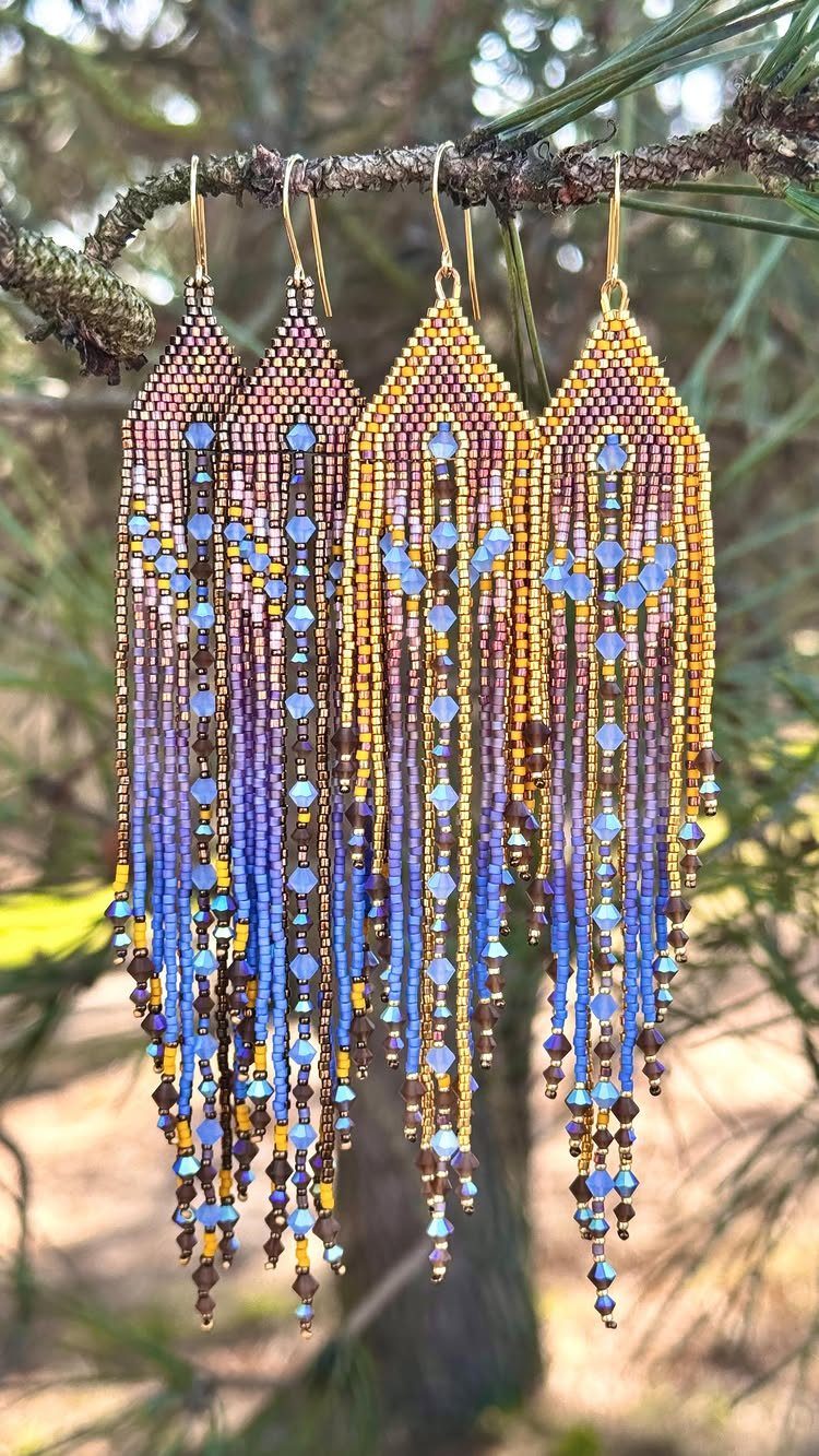 Seed Bead Crafts: 19 Patterns and Projects for 2026 2 Fringe seed bead earrings in gold and blue hanging from a pine branch.