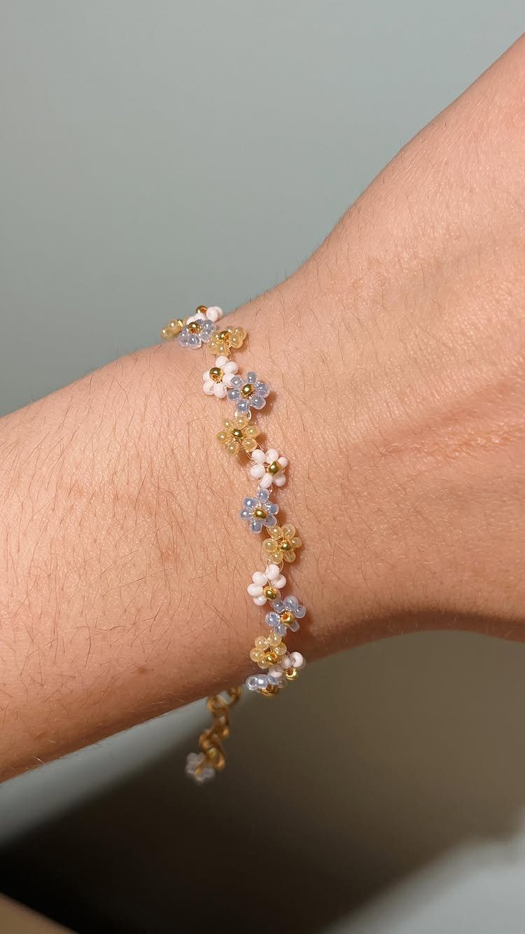 Seed Bead Crafts: 19 Patterns and Projects for 2026 15 Seed bead bracelet with tiny white, yellow, and blue flowers on a wrist