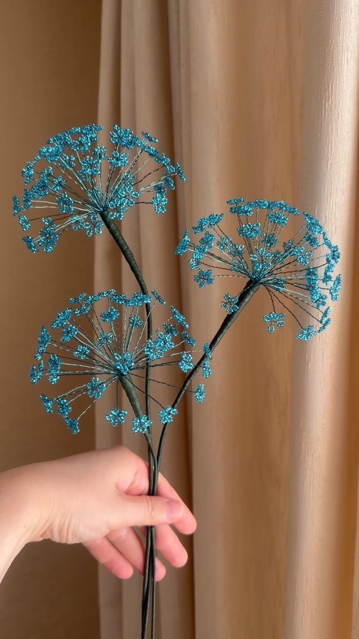 Seed Bead Crafts: 19 Patterns and Projects for 2026 8 Blue seed bead floral clusters on green stems held by a hand