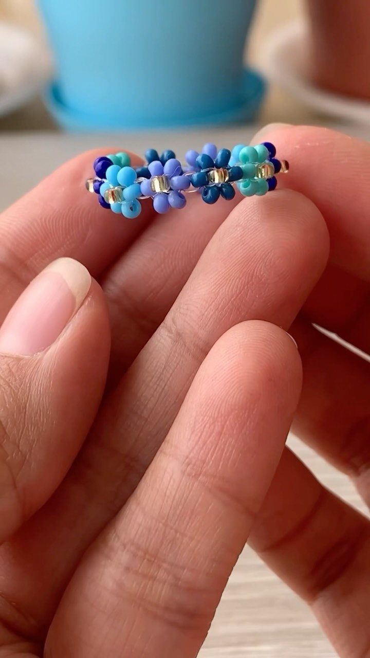 Seed Bead Crafts: 19 Patterns and Projects for 2026 14 Blue seed bead flower ring held between a person's fingers