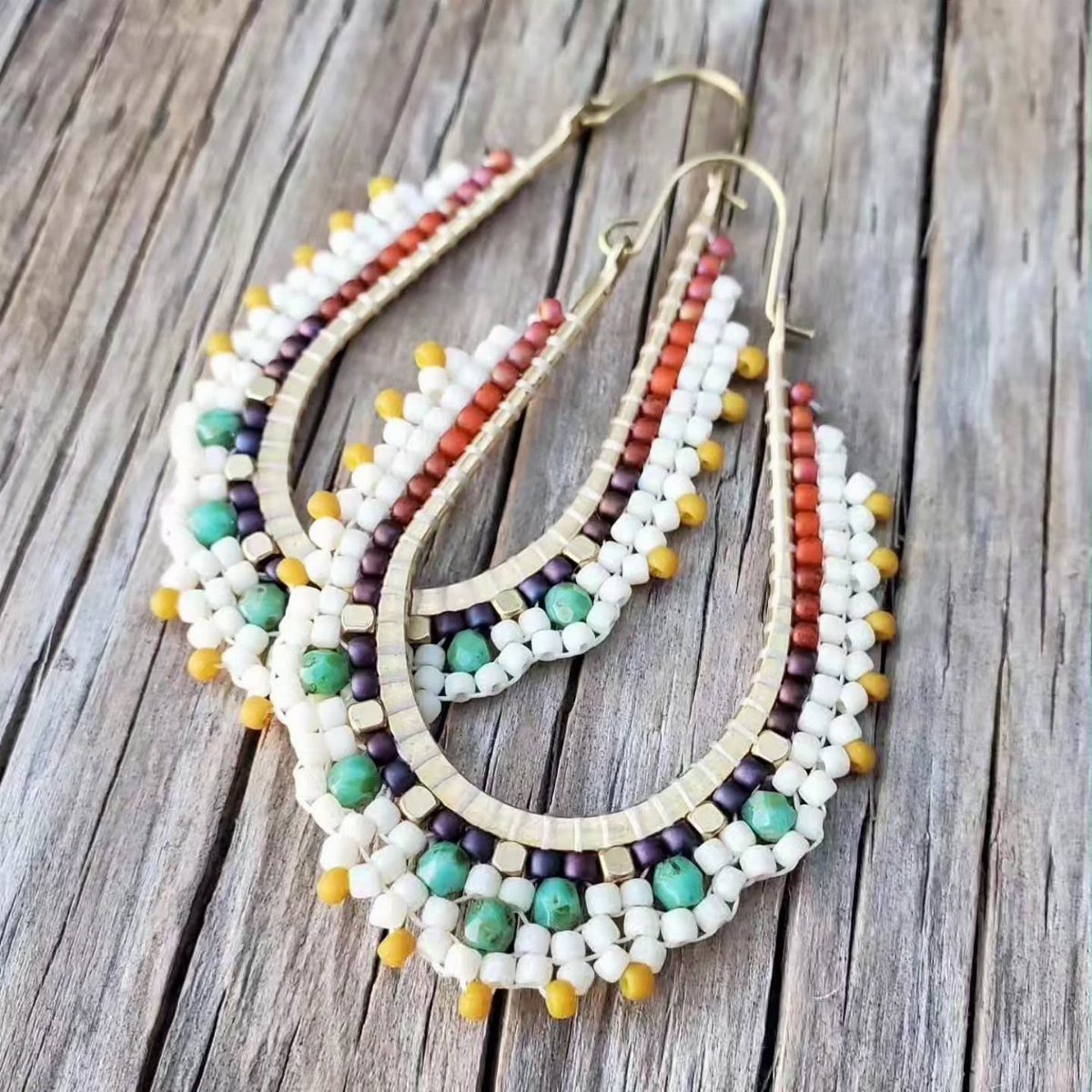 Seed Bead Crafts: 19 Patterns and Projects for 2026 17 Teardrop seed bead earrings with colorful patterns resting on a rustic wooden background.