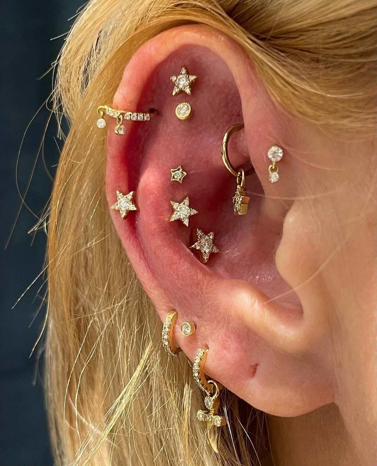 Top of the Ear Piercing Jewelry: 11 Ideas 7 Ear with multiple gold star studs and hoops in a curated piercing layout