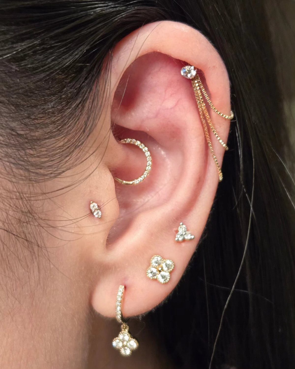 Top of the Ear Piercing Jewelry: 11 Ideas 5 Ear with multiple gold piercings including a helix chain and gemstone studs.