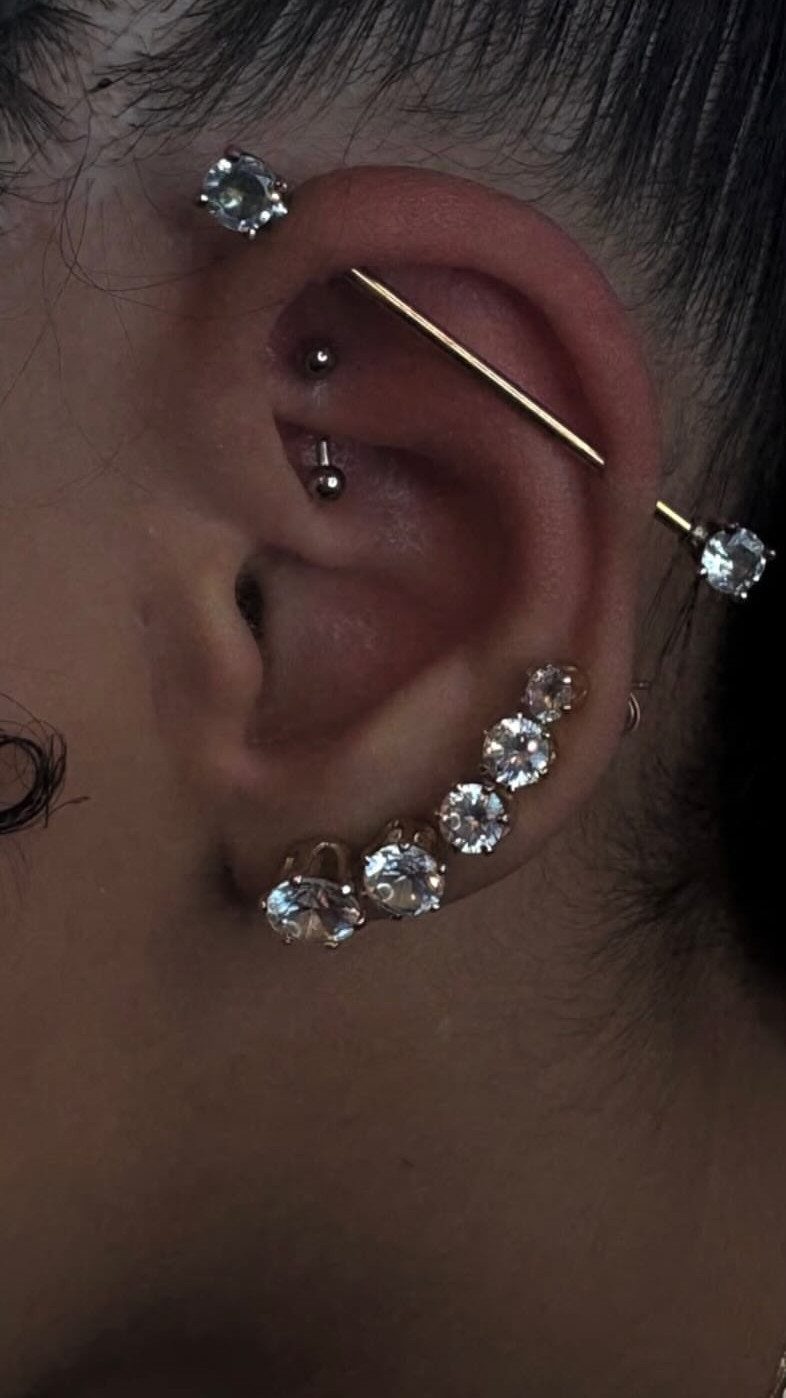 Top of the Ear Piercing Jewelry: 11 Ideas 4 Ear with a gold industrial barbell and multiple sparkling diamond stud piercings.