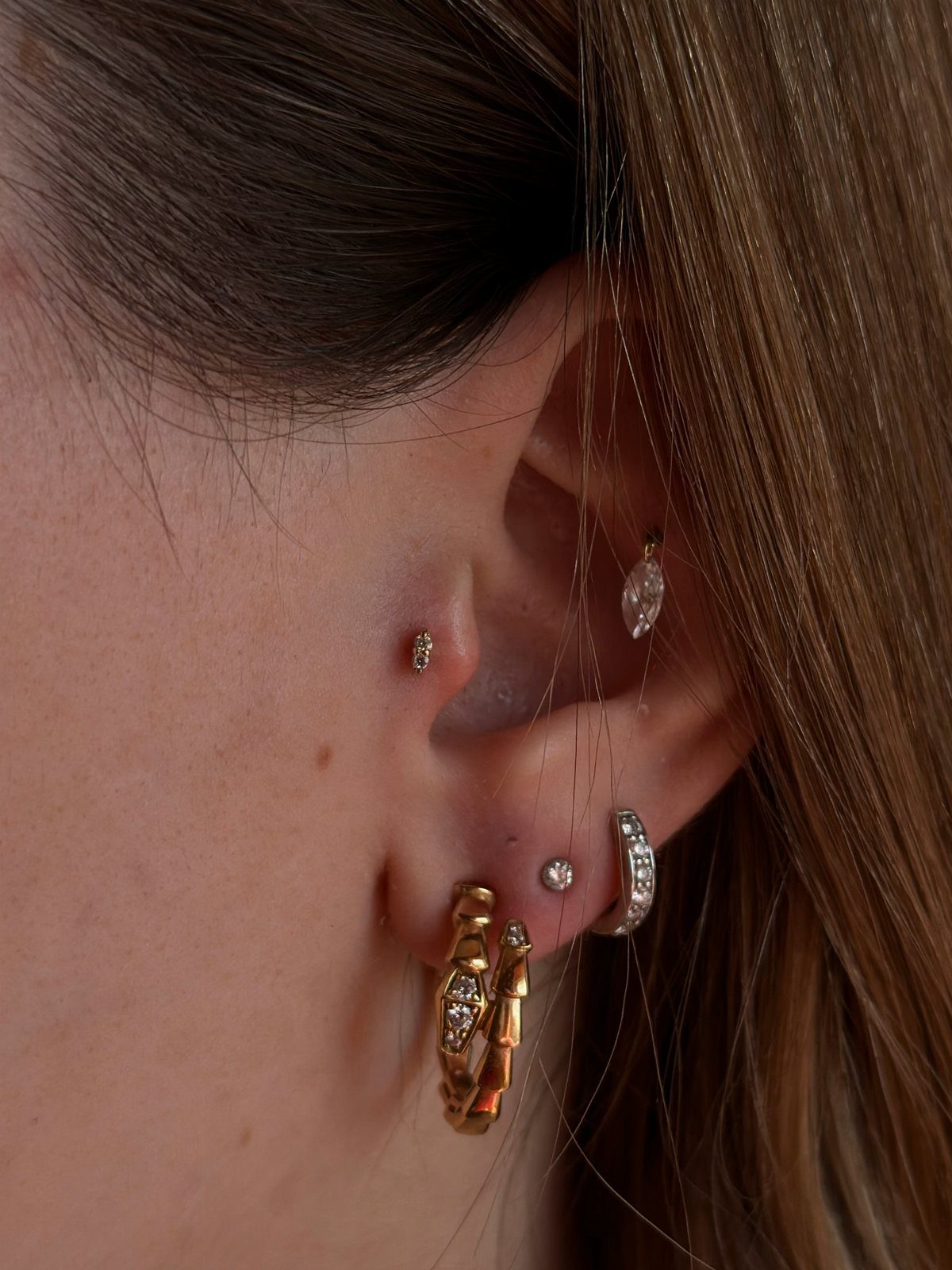 Top of the Ear Piercing Jewelry: 11 Ideas 2 Ear with multiple piercings including a gold tragus stud and helix jewelry.