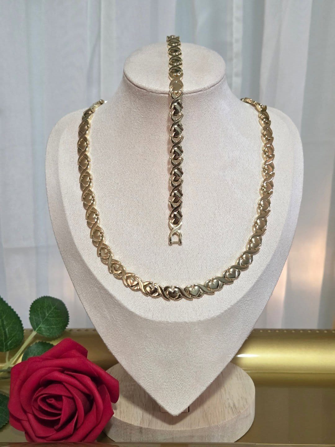 XOXO Jewelry Ideas: 10 Ways to Wear These Timeless Symbols 8 Gold XOXO pattern necklace and bracelet displayed on a white jewelry bust.