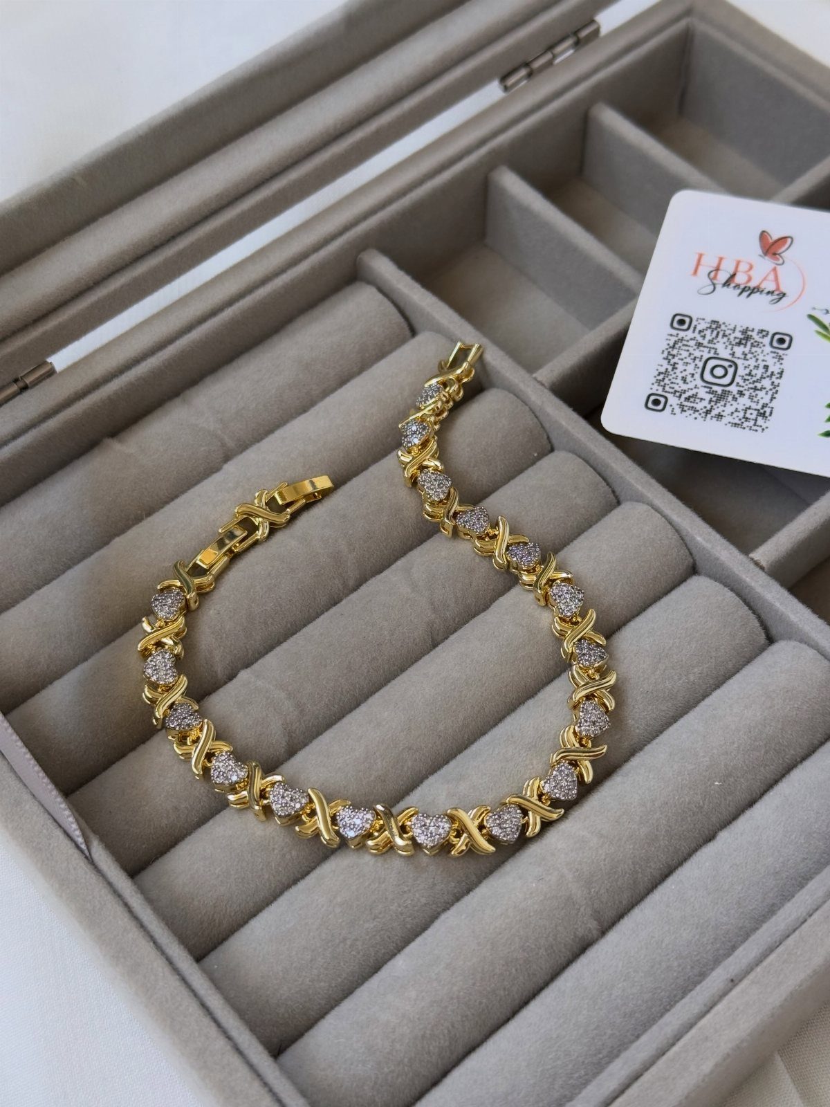 XOXO Jewelry Ideas: 10 Ways to Wear These Timeless Symbols 9 Gold bracelet with gemstone X-shaped links resting in a grey velvet jewelry box